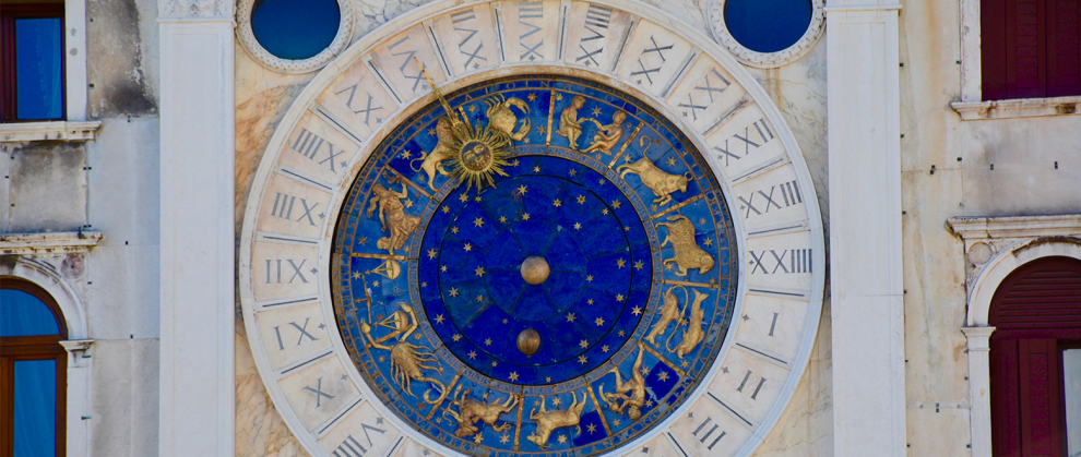Relgio com nmeros romanos e figuras da astrologia