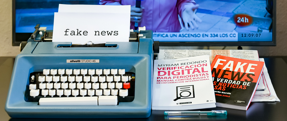 Máquina de escrever com uma folha digitada "Fake News" e dois livros deste mesmo assunto