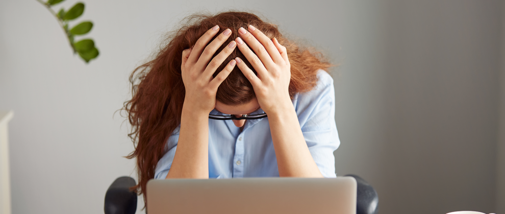 Foto de uma ruiva exausta, trabalhadora de escritrio, de camisa azul e culos