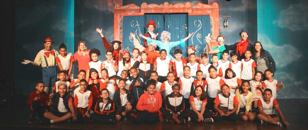 Crianas posando para foto no palco com os atores que protagonizaram o teatro